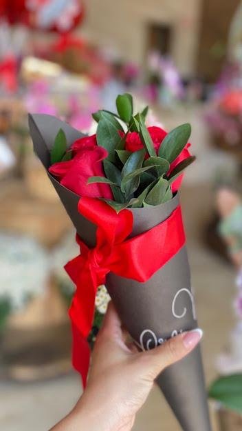 Buquê de rosas vermelhas embrulhado, sendo entregue
